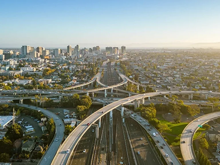 Aerial view of a multi-level highway interchange with city buildings in the background.