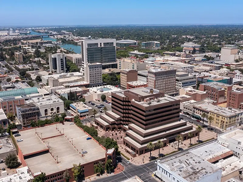 Aerial view of a cityscape with mid-rise buildings and a river in the background.